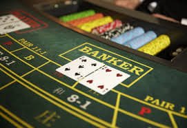 Kumpulan chip casino warna-warni dan kartu di atas meja permainan